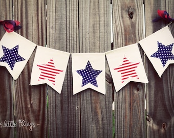 May include: A red, white, and blue bunting with stars on each flag. The bunting is hanging on a wooden fence. The text "lr3s little things" is at the bottom of the image.