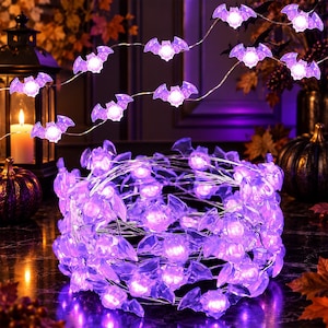 May include: A string of LED lights featuring translucent purple bat-shaped covers. The lights are arranged in a coiled bundle, with additional segments of the light strand extending outward, each bat glowing with a bright purple illumination.