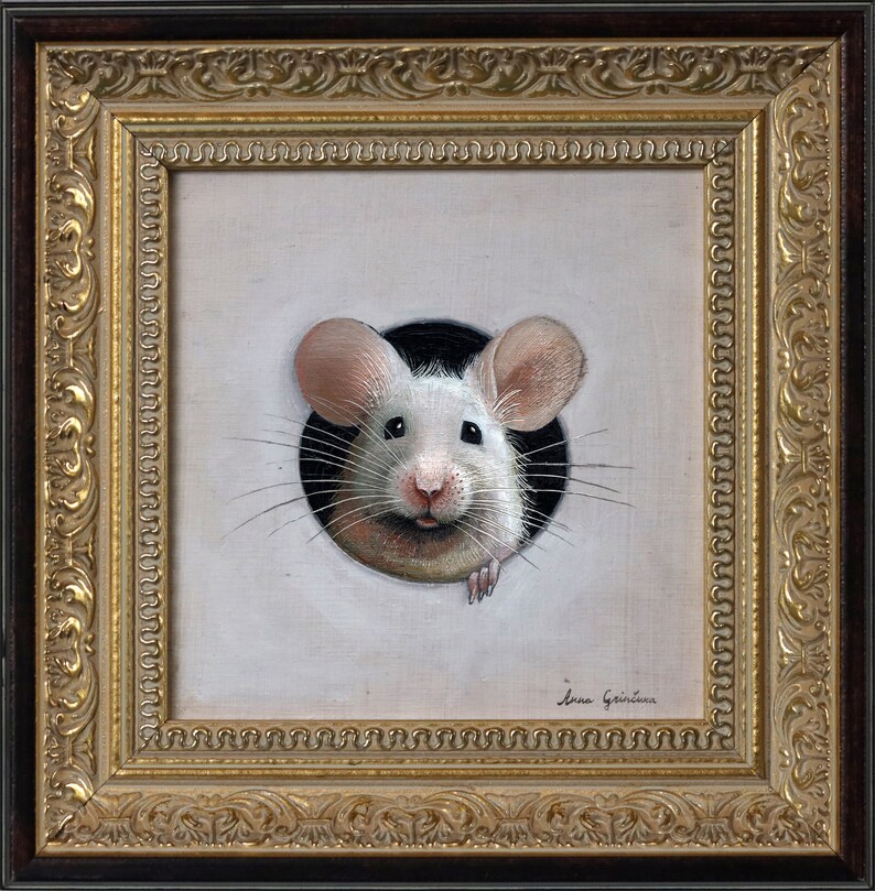 Puede incluir: Un rat&oacute;n blanco con orejas rosas asoma por un agujero en un lienzo blanco. El rat&oacute;n tiene la nariz negra y bigotes. El lienzo est&aacute; enmarcado en un marco dorado adornado.