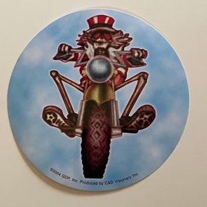 May include: A round sticker with a blue background featuring a skeleton wearing a red, white, and blue hat riding a motorcycle. The text "©2004 GDP, Inc. Produced by C&D Visionary Inc." is at the bottom of the sticker.