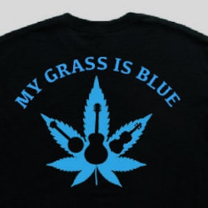 May include: Black t-shirt with a blue marijuana leaf design and the text "My Grass Is Blue".