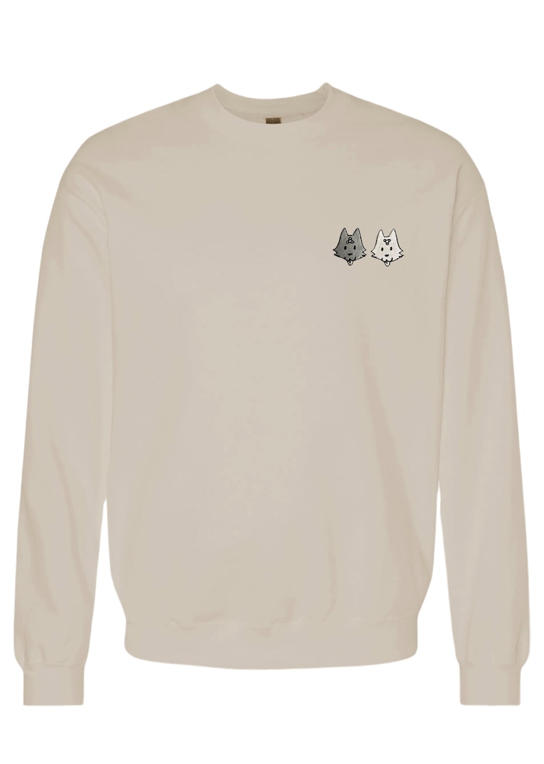 A beige sweatshirt with a small graphic design on the front, featuring two cartoon-like cat faces.