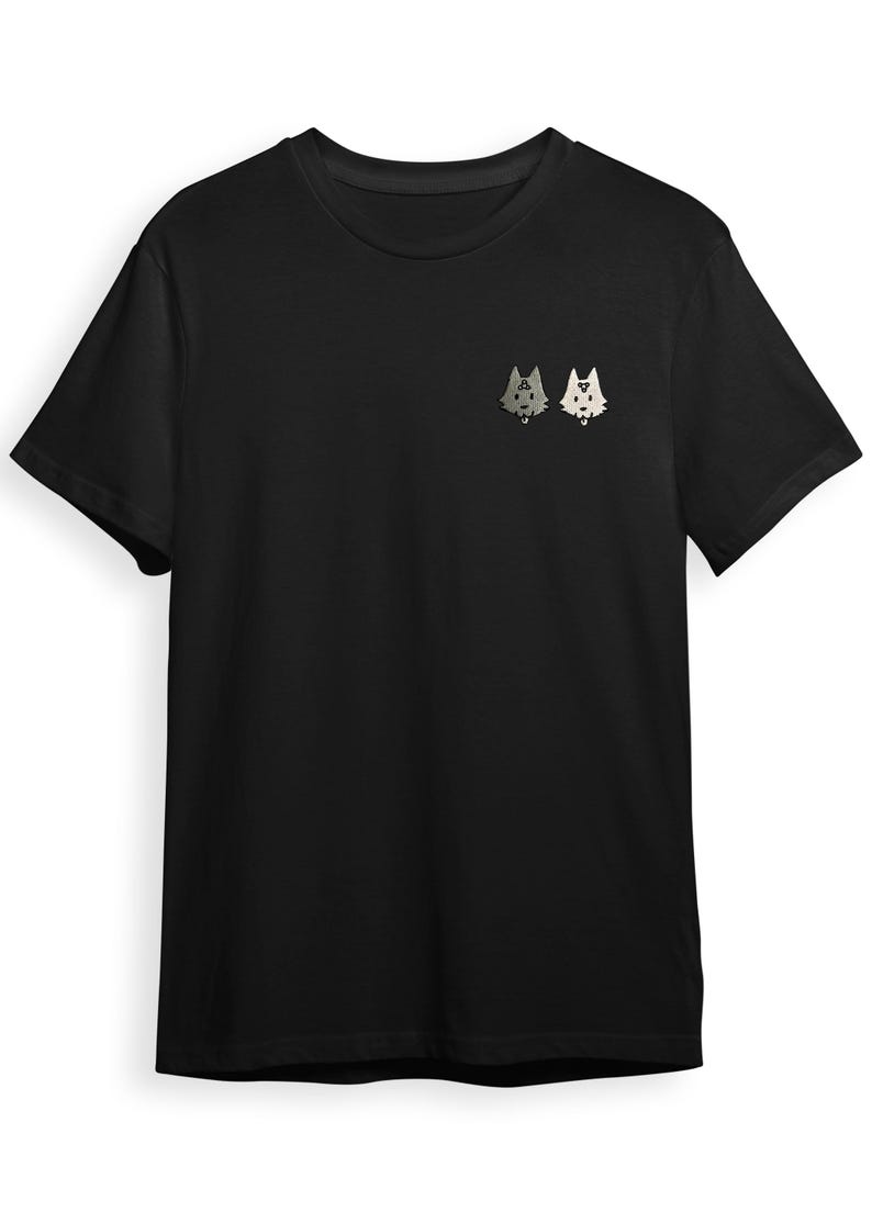 A black t-shirt with a small graphic design on the front, featuring two cartoon-like cat faces.