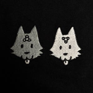 two cartoon-like dog faces, each with a small smile and a small triangle on their heads, set against a black background.