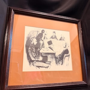 Puede incluir: Una litografía en blanco y negro enmarcada que representa una escena judicial con varias figuras, incluyendo un hombre sentado en primer plano, una figura de pie y otros detrás de un estrado, dentro de un marco de madera marrón oscuro y paspartú naranja.