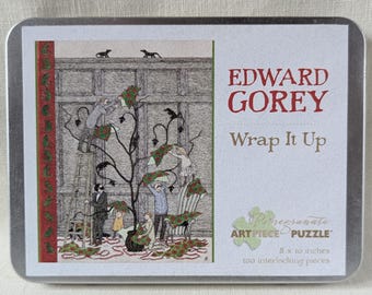 Puzzle de Noël Edward Gorey Wrap It Up, 100 pièces, 20 x 25 cm (boîte en métal)