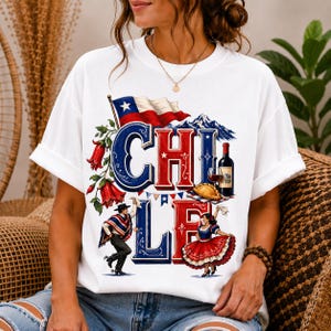 Könnte beinhalten: Ein weißes Kurzarm-T-Shirt mit einem Grafikdruck, der das Wort CHILE in großen blauen und roten Buchstaben zeigt. Das Design umfasst die chilenische Flagge, eine Weinflasche, ein Gebäck, rote Blumen und ein Paar in traditioneller Tanzkleidung.