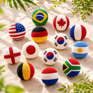 May include: A collection of twelve spherical crochet balls, each featuring the distinct flag design of a different country, including Brazil, Canada, the United States, Germany, France, Japan, South Korea, Argentina, England, Belgium, and South Africa.