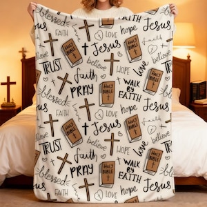 May include: A white throw blanket featuring a repeating pattern of brown illustrated Holy Bibles, brown crosses, and black cursive text including the words Jesus, faith, hope, love, blessed, trust, pray, believe, and walk by faith.