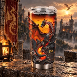Puede incluir: Un vaso de acero inoxidable con un gráfico envolvente de un dragón oscuro y escamoso posado entre llamas de color naranja y rojo. El nombre Ethan está impreso en texto amarillo en el lateral. El vaso incluye una tapa transparente ajustada.