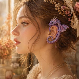 Peut inclure: Une manchette d'oreille en forme de dragon crocheté violet qui s'enroule autour de l'oreille. Le dragon présente une tête détaillée avec de petites cornes, un corps incurvé et des ailes. Une petite perle violette pend à la base de la structure.