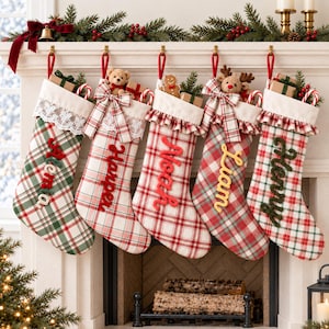 Peut inclure: Cinq chaussettes de Noël en tissu suspendues à une cheminée, chacune avec un motif écossais unique en rouge, vert et blanc. Les chaussettes sont personnalisées avec les noms Alena, Harper, Noah, Liam et Henry en lettres de feutrine.