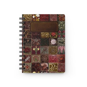 Puede incluir: Un cuaderno de espiral con una cubierta que presenta una cuadrícula de azulejos cuadrados en tonos rojo oscuro, marrón y dorado. Cada azulejo muestra imágenes en relieve de temática natural, incluyendo flores, insectos, animales y patrones geométricos con una etiqueta rectangular en blanco en el centro.