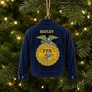 May include: A miniature dark blue corduroy jacket ornament featuring the name HAYLEY in yellow text above an embroidered FFA emblem. The emblem displays an eagle, a shield, an owl, and the words AGRICULTURAL EDUCATION in yellow and blue.