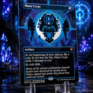 May include: A Mana Crypt trading card featuring a dark blue and black color palette with a central geometric icon. The card text describes an artifact that deals 3 damage upon a lost coin flip and adds two colorless mana. It is displayed on a stand.