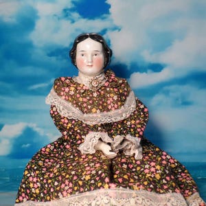 Antique China Doll: Floral Dress, Porcelain Limbs, Brooch Adorned