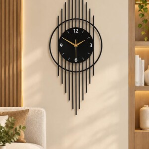 May include: A black metal wall clock featuring a circular face with gold hands and white numerals at 3, 6, 9, and 12. The clock is framed by a series of vertical black metal rods of varying lengths that extend upward and downward in a diamond shape.