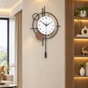 Peut inclure: Une horloge murale composée d'un cadran circulaire blanc avec des chiffres et des aiguilles noirs, encadrée par une structure en métal noir aux lignes géométriques, un petit cercle marron et un pendule vertical suspendu en bas.