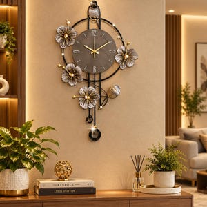 Könnte beinhalten: Eine Wanduhr mit einem runden, dunkelgrauen Zifferblatt, goldenen Zeigern und Ziffern bei 12, 3, 6 und 9 Uhr. Die Uhr ist in eine schwarze Metallstruktur mit metallisch grauen Blumenakzenten, goldenen Staubgefäßen und einem Pendel eingefasst.