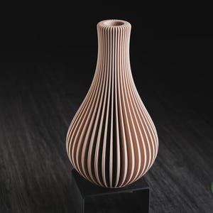 May include: A light peach-coloured vase with a vertical ribbed texture and a narrow neck. The vase features a rounded body that tapers towards the top opening. A small green circular logo with the text h3li&oslash; design is visible in the bottom corner.