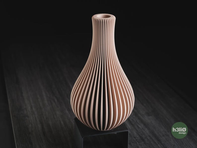 May include: A light peach-coloured vase with a vertical ribbed texture and a narrow neck. The vase features a rounded body that tapers towards the top opening. A small green circular logo with the text h3li&oslash; design is visible in the bottom corner.