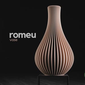 May include: A light peach-coloured vase with a vertical ribbed texture and a narrow neck. The text 'romeu vase' is printed to the left of the object, and a small green circular logo with the text 'h3li&oslash; design' is visible in the bottom right corner.