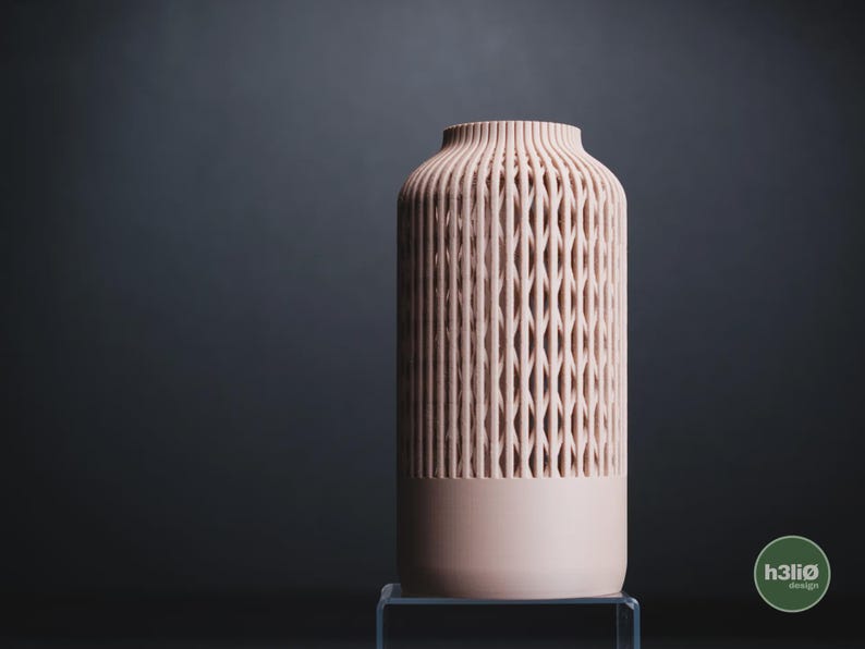 K&ouml;nnte beinhalten: Eine zylindrische Vase in sanftem Pfirsichton mit einem vertikalen Gittermuster auf den oberen zwei Dritteln des K&ouml;rpers. Der Boden ist massiv und glatt, w&auml;hrend der obere Rand gerippt ist. Ein kleines kreisf&ouml;rmiges Logo mit dem Text h3li&oslash; design ist sichtbar.