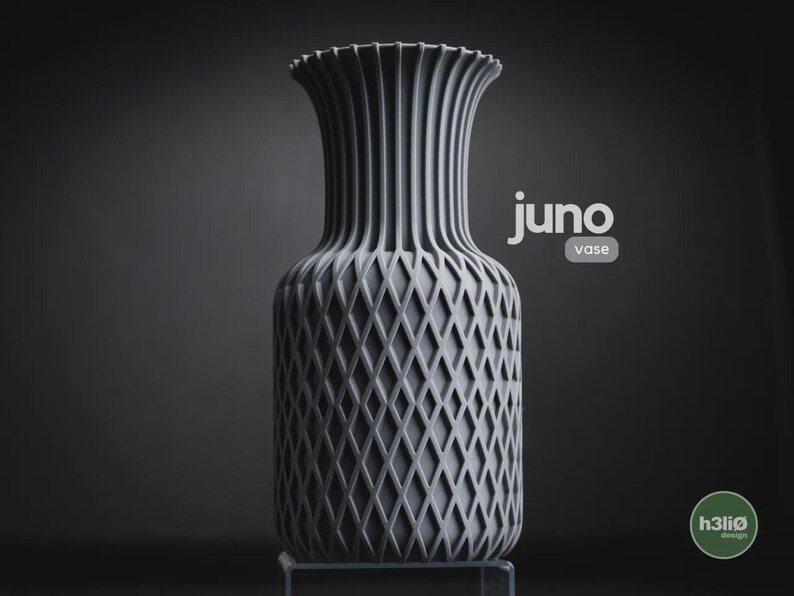 May include: A matte grey vase with a vertical ribbed neck and a diamond-patterned lattice texture on the body. The text "juno vase" is printed in white near the top, and a circular green logo with "h3li&oslash; design" is visible in the bottom corner.
