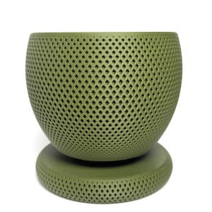 Puede incluir: Una maceta esf&eacute;rica de color verde salvia con un patr&oacute;n de celos&iacute;a en forma de diamante texturizado en toda su superficie. La maceta se asienta sobre una base circular a juego que presenta el mismo dise&ntilde;o geom&eacute;trico recortado y uniforme.