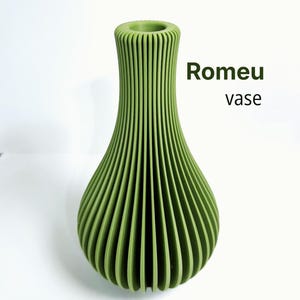 May include: A sage green vase with a vertical ribbed texture and a narrow neck. The text Romeu vase is printed in dark green to the right of the object. The vase has a wide, rounded base that tapers upwards to a circular opening at the top.