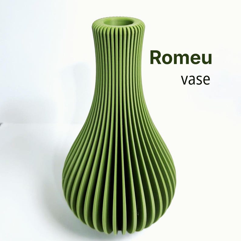 May include: A sage green vase with a vertical ribbed texture and a narrow neck. The text Romeu vase is printed in dark green to the right of the object. The vase has a wide, rounded base that tapers upwards to a circular opening at the top.