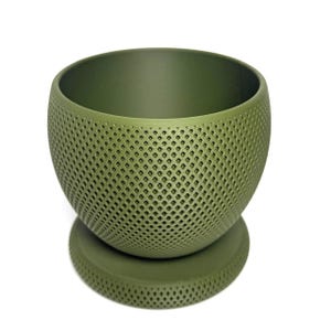 Puede incluir: Una maceta esf&eacute;rica de color verde oliva con un patr&oacute;n de celos&iacute;a de diamantes texturizado en la superficie exterior. La maceta presenta una amplia abertura circular en la parte superior y se asienta sobre una base circular a juego.
