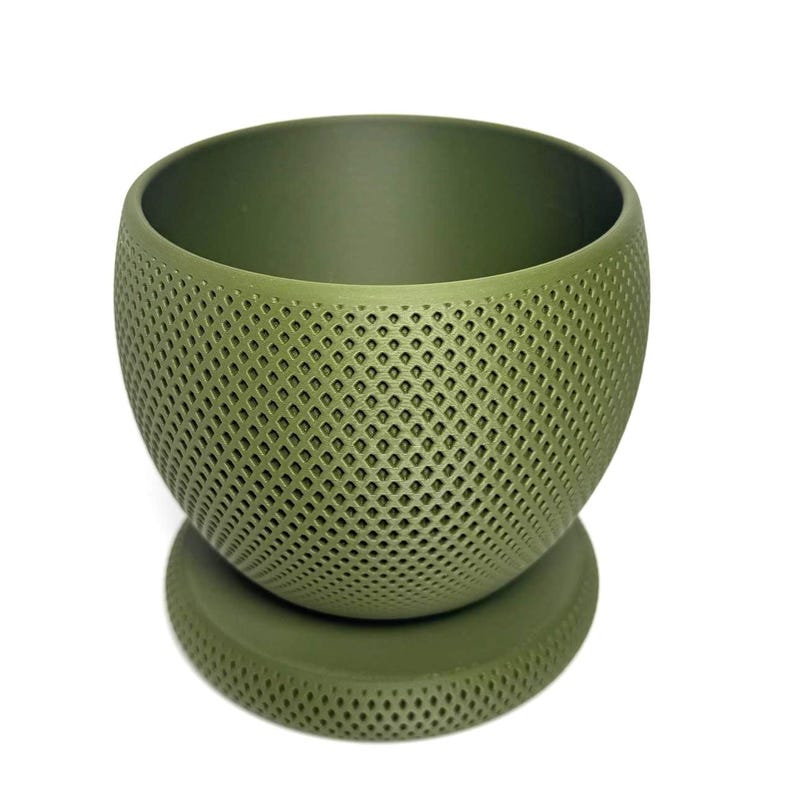 Puede incluir: Una maceta esf&eacute;rica de color verde oliva con un patr&oacute;n de celos&iacute;a de diamantes texturizado en la superficie exterior. La maceta presenta una amplia abertura circular en la parte superior y se asienta sobre una base circular a juego.