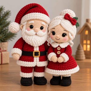 Könnte beinhalten: Zwei gehäkelte Puppen, die den Weihnachtsmann und Frau Weihnachtsmann darstellen. Der Weihnachtsmann trägt einen roten Anzug mit weißem Besatz, einen schwarzen Gürtel mit goldener Schnalle und eine Mütze. Frau Weihnachtsmann hat weißes Haar.