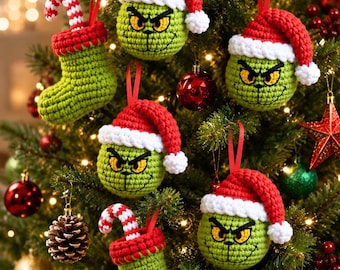 May include: A collection of handmade crochet ornaments featuring green character heads with yellow eyes and black stitched expressions, each wearing a red and white Santa hat, alongside green crochet stockings with red cuffs and candy canes.