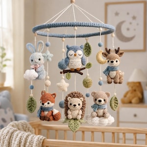 May include: A crochet baby mobile featuring a blue circular frame with hanging plush figures including a light blue rabbit, a grey owl on a branch, a brown deer, a fox, a hedgehog, and a bear, accented with stars, moons, and green leaves.