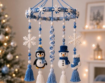 May include: A hanging mobile featuring a circular blue crocheted frame adorned with white snowflakes. Five dangling strands include blue and white beads, white snowflakes, a crocheted penguin, a spiral, a snowman, and a blue and white stocking.