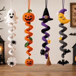 Puede incluir: Cuatro decoraciones colgantes de ganchillo con temas de Halloween: un fantasma blanco con telaraña, una calabaza naranja, un sombrero de bruja negro con escoba y caldero, y una luna creciente amarilla con murciélagos negros, colgados de lazos.