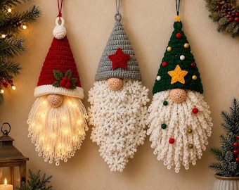May include: Three hanging crochet gnome ornaments. The left gnome has a red hat with holly and integrated warm fairy lights in its white beard. The center gnome has a gray hat with a red star. The right gnome has a green hat with a yellow star.
