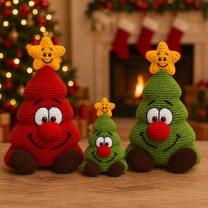 Può includere: Tre figure di albero di Natale all'uncinetto con volti sorridenti, grandi occhi bianchi e nasi rossi. Ogni albero è sormontato da una stella gialla e ha piedi marroni. Un albero è rosso, due sono verdi, tutti con una finitura in filato.
