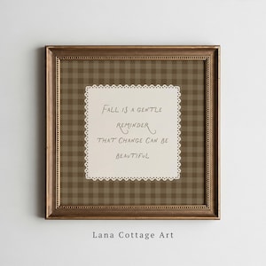 May include: A square wall art piece in a metallic bronze frame featuring a brown and tan gingham background. Centered is a cream-coloured scalloped paper cutout with the text: Fall is a gentle reminder that change can be beautiful.