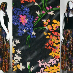 Può includere: Un lungo abito maxi nero con stampa floreale. L'abito ha un corpetto aderente e una gonna fluida. La stampa floreale presenta una varietà di colori, tra cui rosa, giallo, arancione e blu. L'abito è accessoriato con un foulard abbinato.
