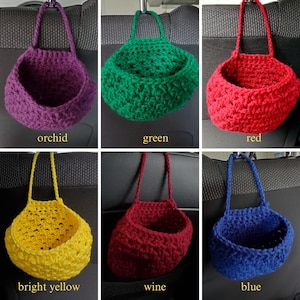 Op de afbeelding: Set van 10 gebreide hangmanden in verschillende kleuren, waaronder orchidee, groen, rood, felgeel, wijnrood en blauw. De manden zijn gemaakt van een zacht, getextureerd garen en zijn perfect om elke kamer een vleugje handgemaakte charme te geven.