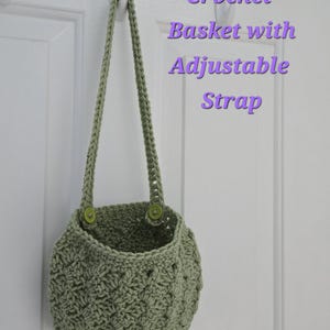 May include: A green crocheted basket with an adjustable strap hanging on a white door. The strap has green buttons.