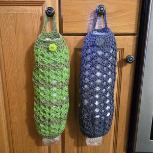 Puede incluir: Dos bolsas de crochet para guardar bolsas de pl&aacute;stico de la compra. Una bolsa es verde y la otra es azul. Ambas bolsas est&aacute;n colgadas de ganchos en una puerta de armario.