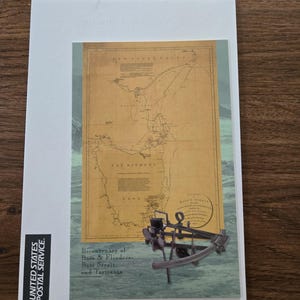 May include: A postcard featuring a vintage map of Bass Strait and Tasmania, with a detailed illustration of a sextant. The text reads "Bicentenary of Bass & Flinders - Bass Strait and Tasmania". The United States Postal Service logo is on the left.
