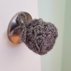 May include: A gray crocheted door knob cover with a tied bow.