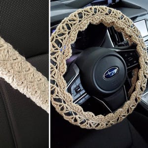 May include: A beige crochet steering wheel cover and matching seat belt cover. The steering wheel cover is circular with an openwork design. The seat belt cover is a long, cylindrical shape. Both items are made of a textured, woven material.