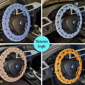 May include: Four crochet steering wheel covers in different colors: light blue, light grey, tan, and yellow-orange. Each cover is on a black steering wheel inside a car. The covers have a decorative openwork design. The text "Victoria's Crafts" is in the image.