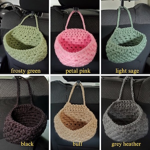 Op de afbeelding: Zes gehaakte autostoelorganizers in verschillende kleuren:  frosty green, petal pink, light sage, zwart, buff en grijs heather. Elke organizer hangt aan een hoofdsteunhaak.